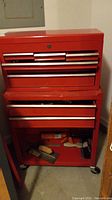 Full view of red 2-piece rolling tool box with top and bottom sections, bottom compartment door open showing tools inside