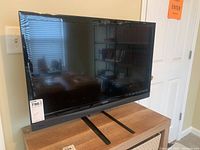 Front view of the 32 inch Vizio TV with stand on a wooden surface.