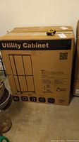 Boxed utility cabinet with visible label and tape measure on top providing scale reference.