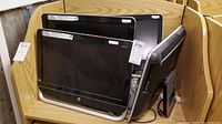 Four HP Pavilion 20 all-in-one computer monitors grouped together on a wooden shelf. They have black glossy bezels and silver stands.