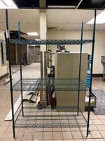 Full front view of the metal NSF shelf unit showing four wire shelves and green coated frame.