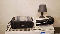 Canon MG2220 and HP Officejet 6000 printers side by side with desk lamp on top of HP printer.