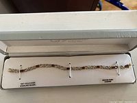 Full view of the bracelet in presentation box showing overall design with 18KT gold over sterling silver and ruby and diamond gems