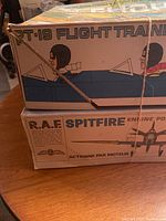 Stacked boxes of PT-19 Flight Trainer and RAF Spitfire by Cox with string tying