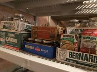Photo showing multiple boxes of Bernardin canning jars including 250ml and 500ml sizes, decorative and regular mason jars, and snap lids on a shelf.