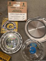 Photo showing multiple sizes and types of circular saw blades including boxed Forrest MFG finger joint set and packaged Boomerang Tools melamine blade.