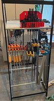 Full view of mobile metal stand loaded with various clamps