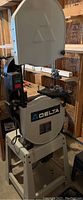 Front view of Delta band saw on stand showing blade cover, table and base.