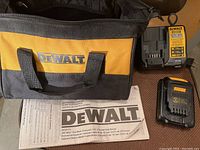 Carrying case with DeWalt branding, instruction manual, battery charger, and battery charger plug adapter