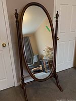 Full view of mirror leaning in room showing oval glass and stand