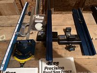 Overview of three blue anodized aluminum rails with white scales, two adjustable fence assemblies and one protractor gauge, plus instruction manuals.
