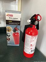 Photo showing the Kidde fire extinguisher with box and label in French indicating it is a 5-B:C rating suitable for kitchen, auto, and marine use.