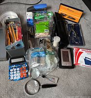 Full view of lot including calculator, pens, magnifying glasses, tape dispensers, gloves, clips, and clock