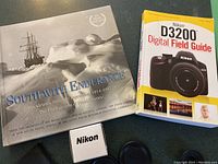 Photo showing two photography books and a Nikon lens cap box on a table