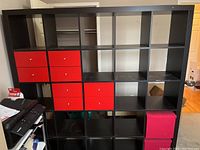 Full view of shelving unit showing 8 red drawers, 2 red storage boxes, pencil sharpener on one side, and open shelving compartments.