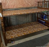 Full view of the vintage wooden bunk bed frame showing two mattress platforms covered in patterned vinyl.