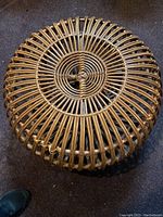 Top view of brown wicker foot stool showing circular woven pattern with a small gap in the center.