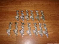 Top view showing all 13 silver-finished phoenix/peacock brooches arranged on wood floor, displaying their detailed rhinestone decorations.