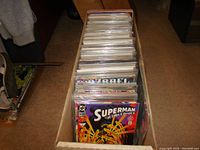 Box packed with 200+ bagged comic books mostly from DC, Marvel and Image brands upright in a single row.