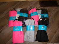 Set of nine scarves in pink, black, and gray still on hangers and wrapped in plastic packaging.