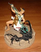 View of the Promethea statue on a wooden floor showing the figure holding green magical serpent on a cracked base