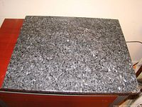 Top view showing speckled black pearl granite surface on table top with polished finish.