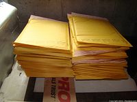Stack of yellow bubble mailers piled on a surface, showing quantity and general condition