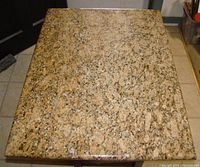 Top down view of rectangular granite piece showing polished surface with mixed beige, brown, black, and white speckled granite pattern.