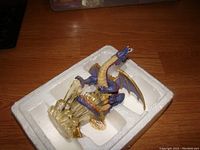 Ice dragon figurine displayed in white foam packaging showing translucent ice base and blue accents