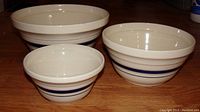 Photo showing three ceramic mixing bowls arranged on a wood countertop, displaying the blue stripe design and bowl dimensions.