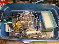 Large plastic tote containing various household items including tools, light fixtures, and a hand mixer.