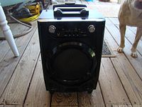 Front view of Vibe DG-17KR-BLK portable wireless Bluetooth speaker showing the speaker grill, handle on top, and wheels at bottom.