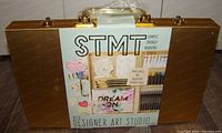 Front view of the sealed STMT D.I.Y Designer Art Studio gold case with label showing included items