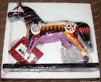 Front and side views of Trail of Painted Ponies Prairie Horizon ceramic horse figurine with colorful abstract geometric patterns and black base.