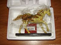 Photo showing the horse figurine wrapped in plastic inside a styrofoam container, highlighting size and packaging.