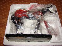 Figurine in the original styrofoam package wrapped in plastic, showing the item for protection and packaging condition.