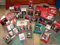 Lot of 29+ vintage Christmas ornaments with original packaging displayed on a carpet. Boxes include Hallmark Keepsake ornaments and Lump of Coal tins, all sealed and undamaged.