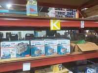 Four boxed ActiveAQUA Air Pump 110 units on warehouse shelf.