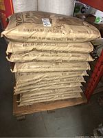 Stacked 50 L bags of potting mix on a wooden pallet under shelving