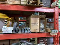 Shelf overview showing boxes of fluorescent tubes, blister packs of hanging clips, and coiled yellow cord