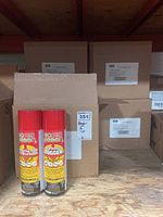 Two red Doktor Doom Go Green Fogger cans in front of stacked cardboard boxes