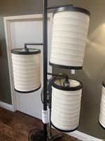 Close-up photo of the cream cylindrical fabric shades with black metal rims on one of the standing lamps.