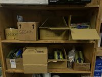 Shelves holding multiple cardboard boxes labeled SEC-0125, SEC-05C, SEC-1001, SEC-0503 containing assorted scissors and pruners