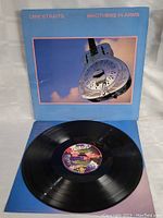 Vinyl LP record partially removed from sleeve, showing center label artwork and vinyl surface.