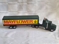 Full left side view of the green tractor and yellow trailer with Mayflower logo.