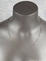 Straight frontal view of the silver box chain necklace on display bust, showing length and chain style.