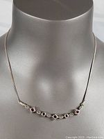 Front close-up image of the sterling silver necklace showing garnet stones and chain detail.
