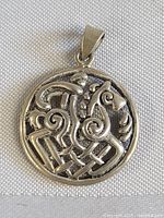 Front view of circular sterling silver pendant showing stylized horse and rider design with Celtic knot elements.