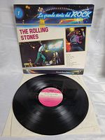 The black vinyl record placed in front of the sleeve, showing the pink and white label with The Rolling Stones name and track credits.