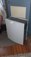 Front and side view of Aerus HepaSilent air purifier in a room with visible power cord and control knob on front panel.